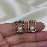 Gold quadrate stud earrings with a single freshwater pearl in each.