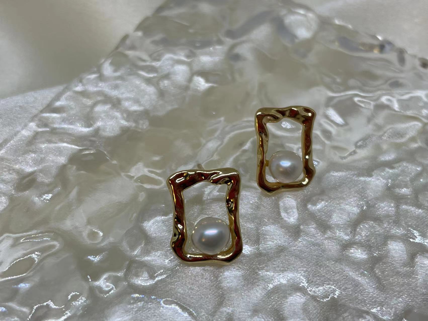 Gold quadrate stud earrings with a single freshwater pearl in each.