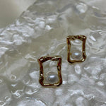 Gold quadrate stud earrings with a single freshwater pearl in each.