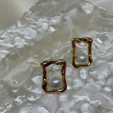 Gold quadrate stud earrings with a single freshwater pearl in each.