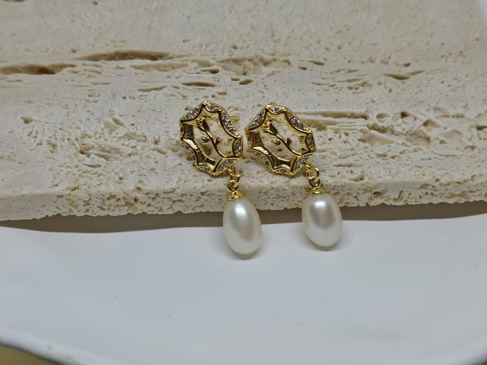 Gold-plated earrings with a vintage design, clear stones, and dangling freshwater pearls.