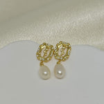 Gold-plated earrings with a rose design, clear stones, and dangling freshwater pearls.