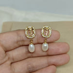 Gold-plated earrings with a rose design, surrounded by small gems, and a dangling pearl.