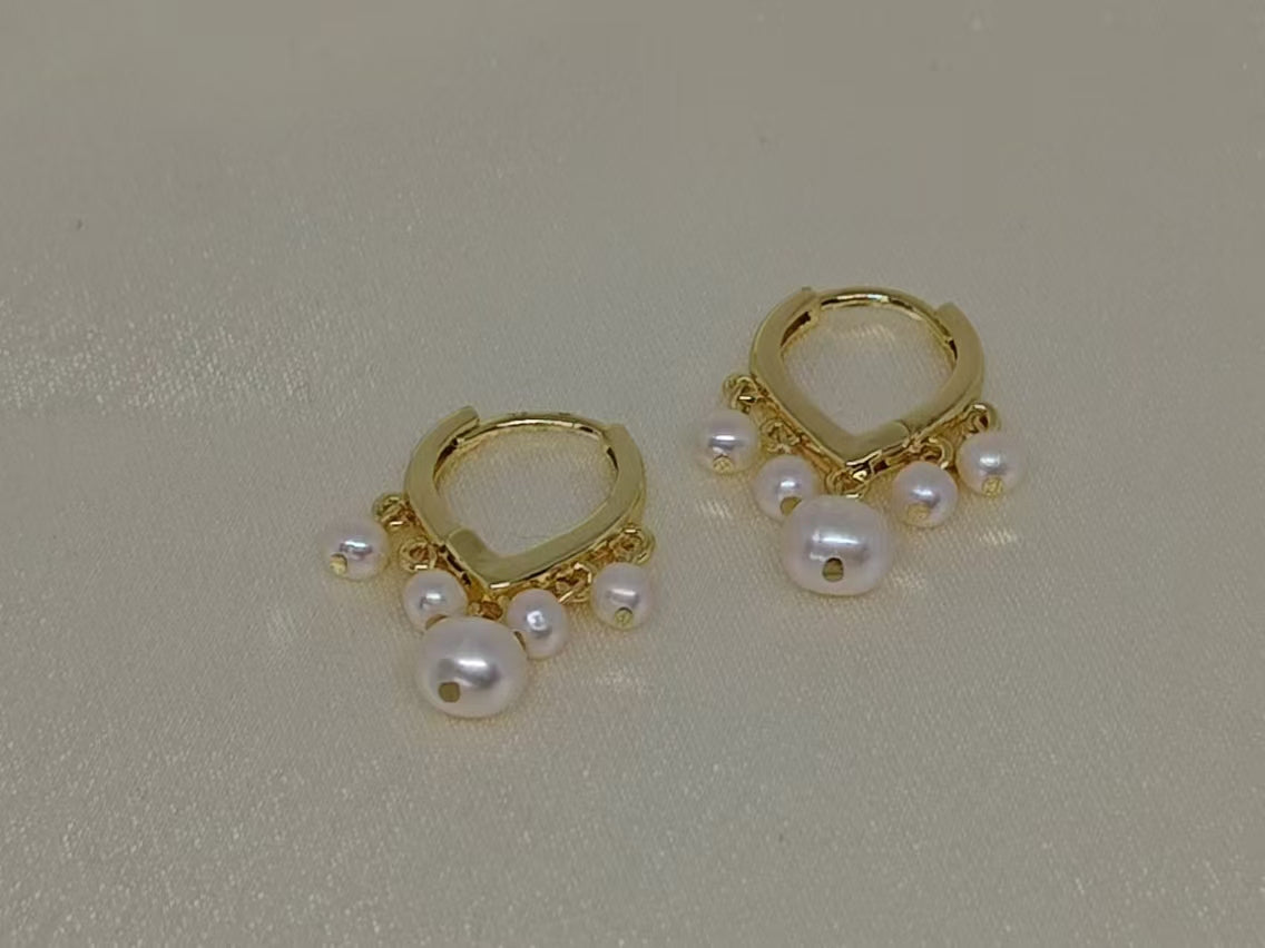 Two gold hoop earrings each adorned with five freshwater pearls.