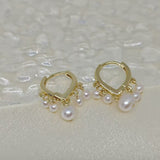 Two gold hoop earrings with five freshwater pearls each are displayed on a white surface.