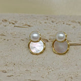 Two gold-framed earrings, each with a white pearl above a mother-of-pearl disc.
