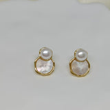 Two gold-framed earrings with a white pearl atop a mother-of-pearl disc.