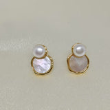 Two gold-framed earrings, each with a white pearl atop a mother-of-pearl disc.