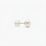 A single pearl stud earring with a gold post and a clear plastic backing.
