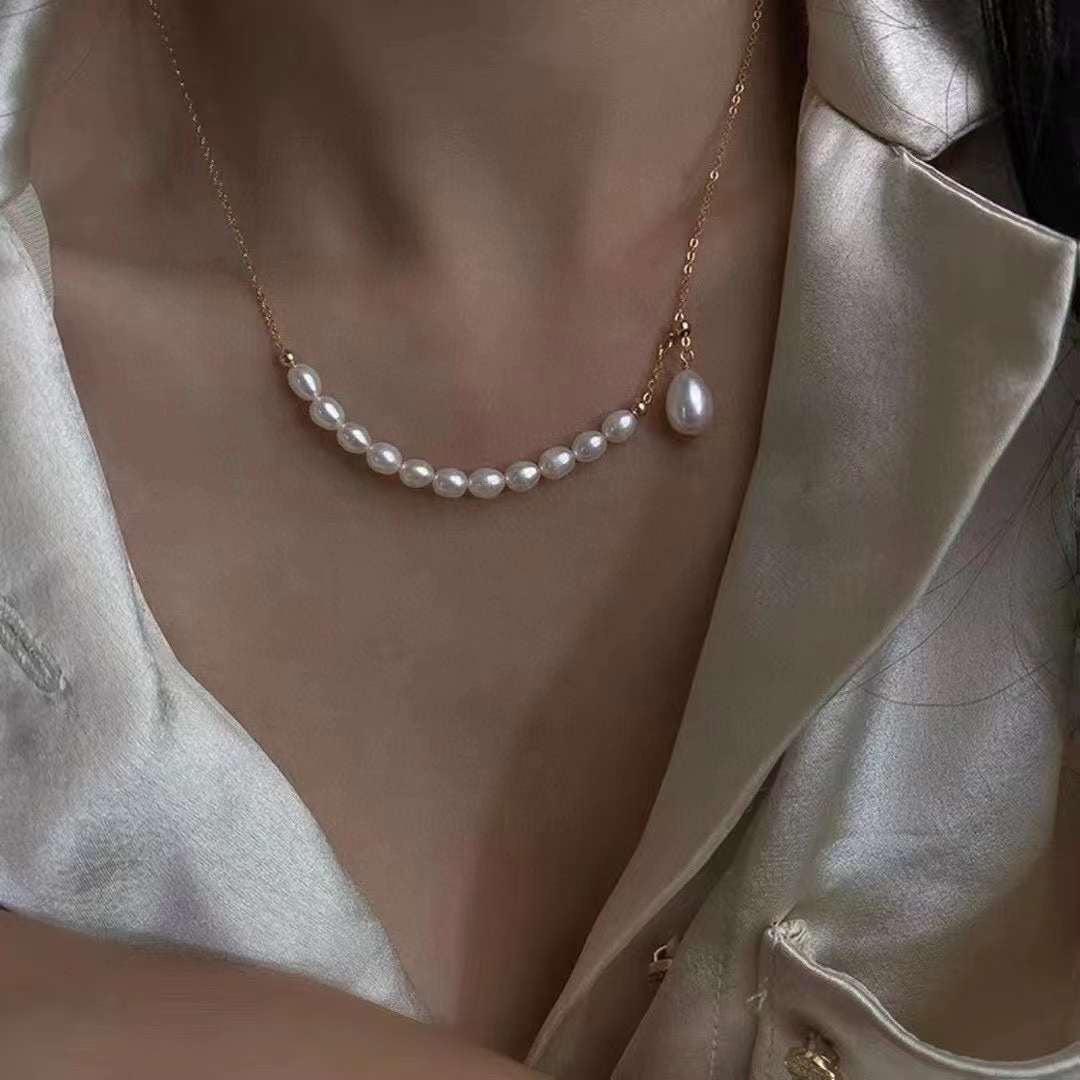 A rice-shaped pearl necklace with a gold-plated chain and a single drop pearl.
