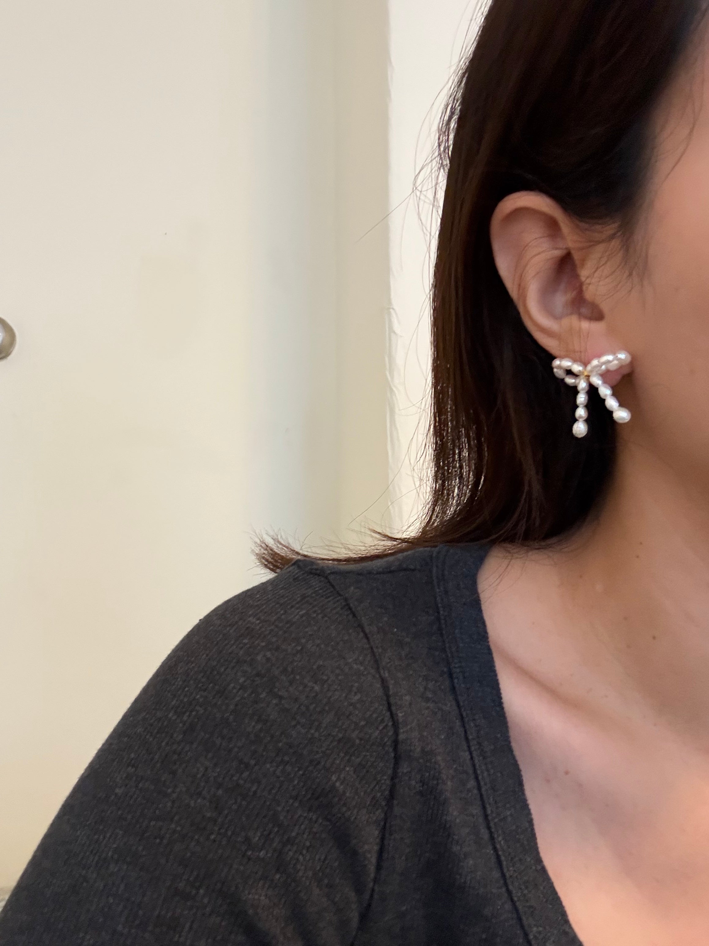 Delicate sterling silver stud earrings with butterfly bow design and luminous pearls.