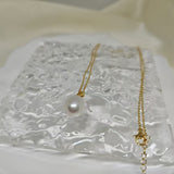 A gold chain necklace with a large, off-round white freshwater pearl pendant.