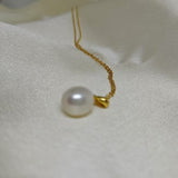 White freshwater pearl necklace with a gold chain on a white fabric background.