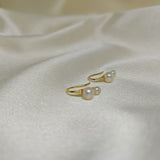 Gold-plated freshwater pearl stud earrings with curved hooks on white fabric.