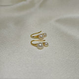 Gold-plated freshwater pearl stud earrings with curved hooks on a white fabric background.