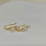 Gold-plated freshwater pearl stud earrings with curved hooks.