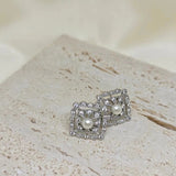 Silver quadrate stud earrings with a central freshwater pearl and surrounding small diamonds.