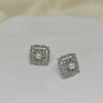 A pair of silver square stud earrings with a central pearl surrounded by small diamonds.