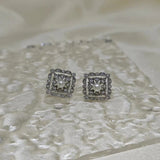 Silver quadrate vintage stud earrings with a central freshwater pearl and surrounding diamonds.