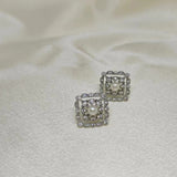 Silver quadrate stud earrings with a central pearl surrounded by small diamonds.
