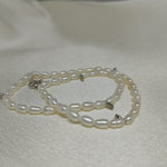 A double-wrapped freshwater pearl bracelet with silver clasps lies on a white surface.