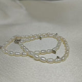 A double-wrapped freshwater pearl bracelet with silver clasps lies on a white surface.