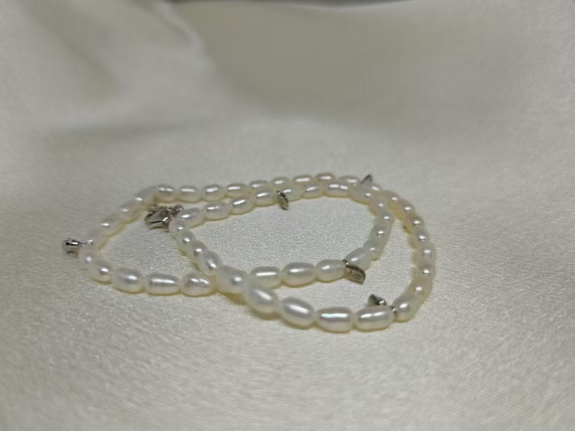 A double-wrapped freshwater pearl bracelet with silver clasps lies on a white surface.