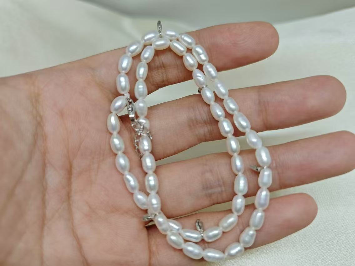 A double-wrapped freshwater pearl bracelet is held in a person's hand.