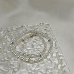 Double-wrapped freshwater pearl bracelet on a textured clear surface.