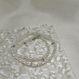 Double-wrapped freshwater pearl bracelet on a textured clear surface.