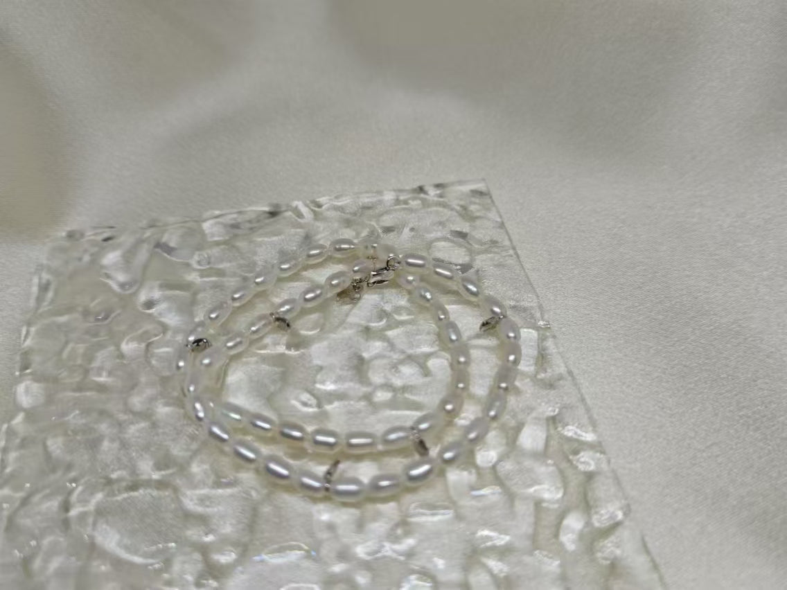 Double-wrapped freshwater pearl bracelet on a textured clear surface.