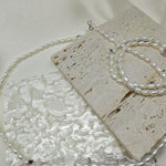 A double-wrapped freshwater pearl bracelet is displayed on a textured stone surface.