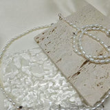 A double-wrapped freshwater pearl bracelet is displayed on a textured stone surface.