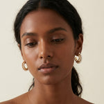 A model wears Caellia 14K gold bead hoop earrings accented with white freshwater pearls.