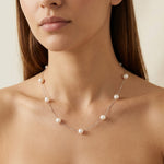 A woman wears a Caellia dainty 14K gold chain necklace featuring spaced freshwater pearls.