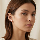 A woman wears Caellia 18K gold and sterling silver freshwater pearl stud earrings.