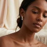 A model wears Caellia 14K gold drop earrings featuring three white freshwater pearls.