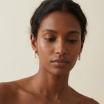 A model wears Caellia 14K gold drop earrings featuring three white freshwater pearls.