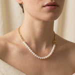 A person wears a Caellia 14K gold plated necklace featuring freshwater pearls and a toggle clasp.