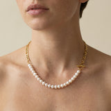 A person wears a Caellia 14K gold plated necklace featuring freshwater pearls and a toggle clasp.