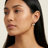 A model wears Caellia 14K gold musical note stud earrings featuring two freshwater pearls.