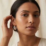 A model wears Caellia sterling silver hoop earrings featuring a ringlet of freshwater pearls.