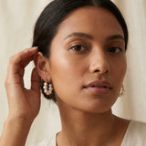 A model wears Caellia sterling silver hoop earrings featuring a ringlet of freshwater pearls.