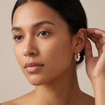 A model wears Caellia sterling silver hoop earrings featuring a ringlet of freshwater pearls.