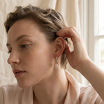 A model wears Caellia sterling silver earrings featuring a luminous freshwater pearl drop.