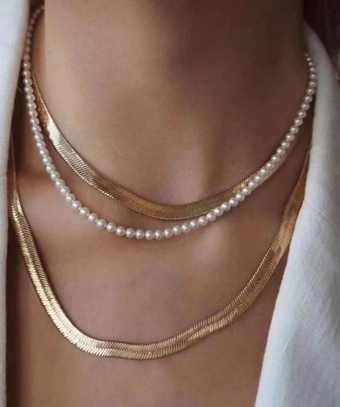 A Caellia layered necklace featuring a delicate freshwater pearl strand and gold herringbone chains.