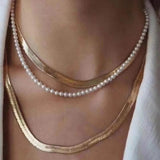 A Caellia layered necklace featuring a delicate freshwater pearl strand and gold herringbone chains.