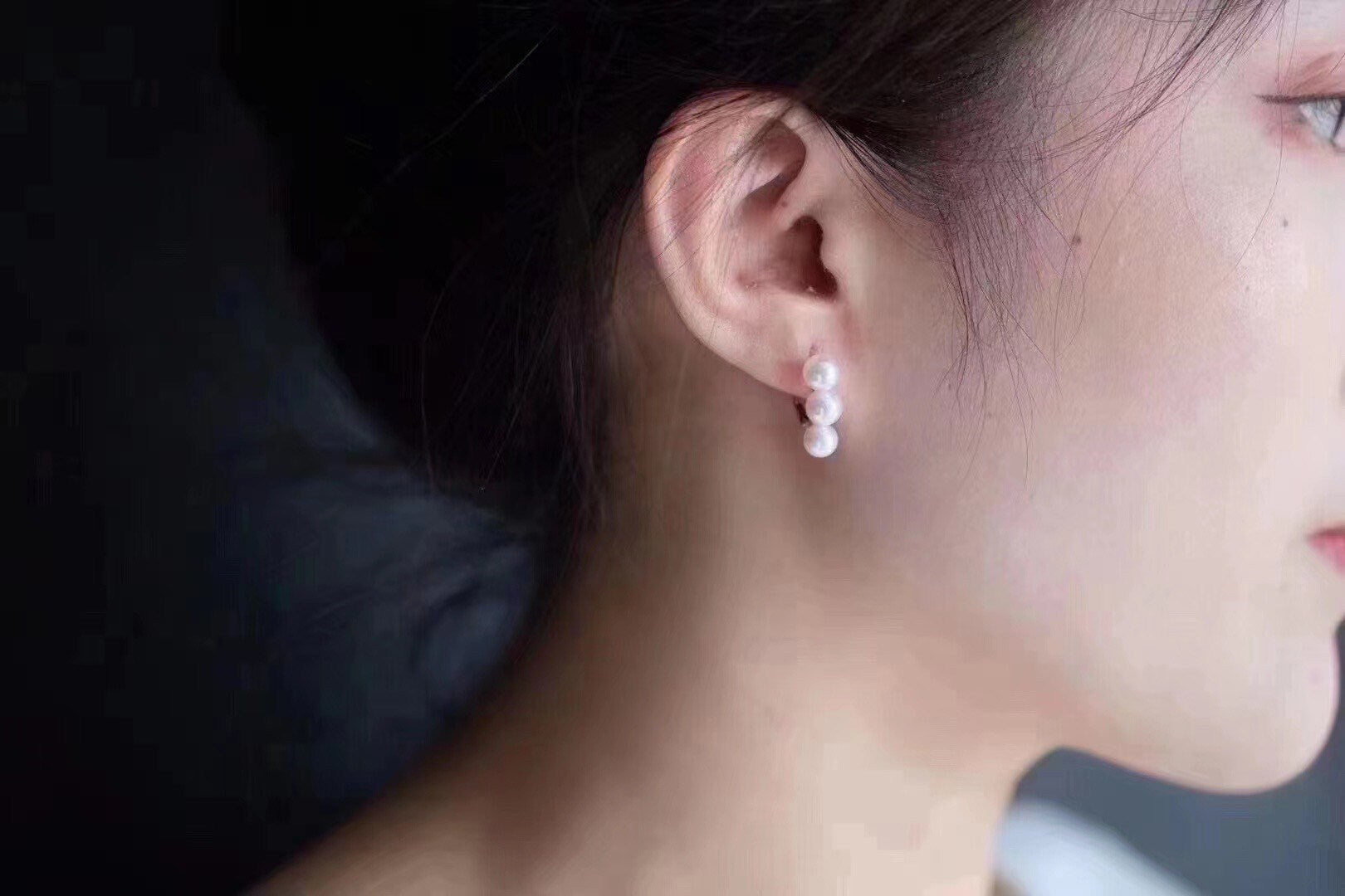 A model wears Caellia 14K gold plated drop earrings featuring three small freshwater pearls.