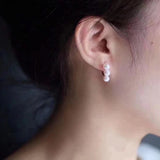 A model wears Caellia 14K gold plated drop earrings featuring three small freshwater pearls.
