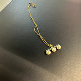 A gold-plated necklace features a green bar pendant with three pearls.